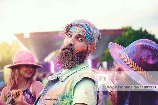 Junge erwachsene Freunde tanzen auf dem Festival mit farbigem Kreidepulver bedeckt