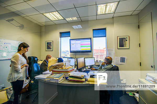 Drei Büroangestellte an Schreibtischen im Büro