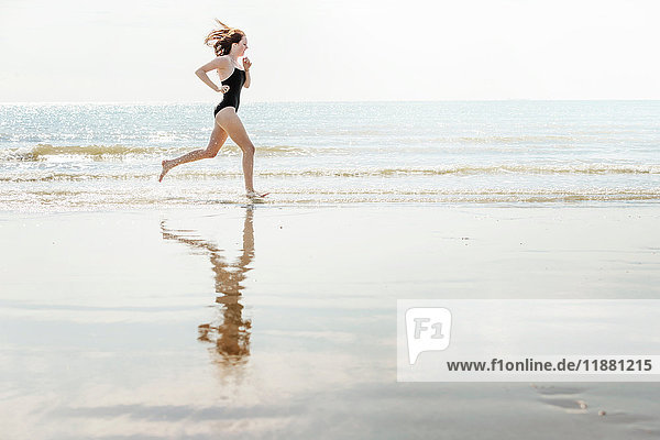Junge Frau läuft am Strand  Folkestone  UK