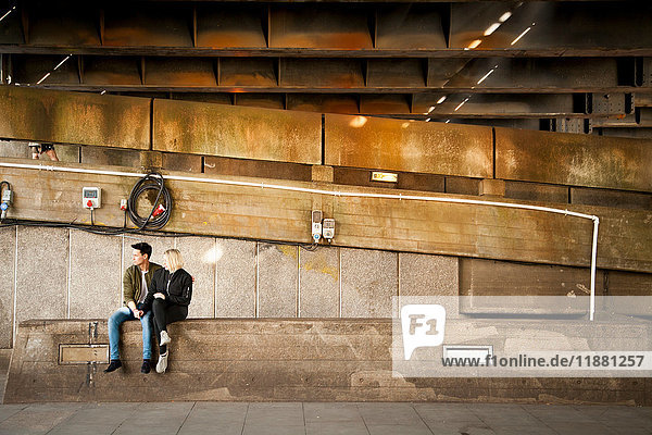 Junges Paar  das unter der Brücke sitzt und sich entspannt