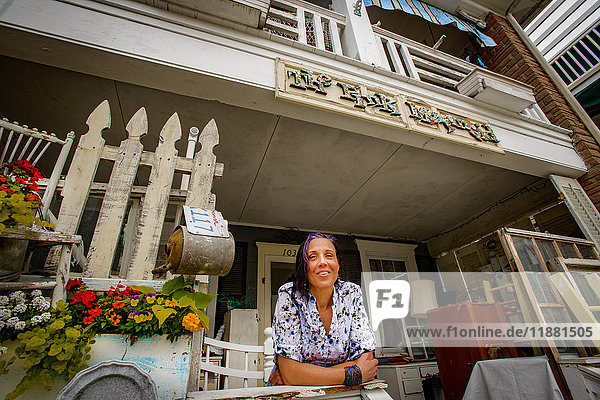 Porträt einer Ladenbesitzerin in einem schäbigen  schicken Laden vor der Veranda