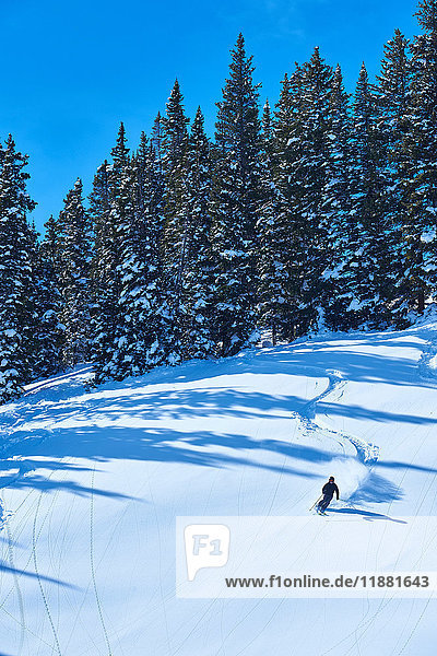 Fernansicht eines Mannes beim Skifahren in schneebedeckter Landschaft  Aspen  Colorado  USA