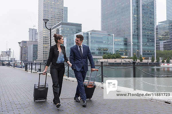 Geschäftsmann und Geschäftsfrau  die Gepäckwagen ziehen  Canary Wharf  London  Großbritannien