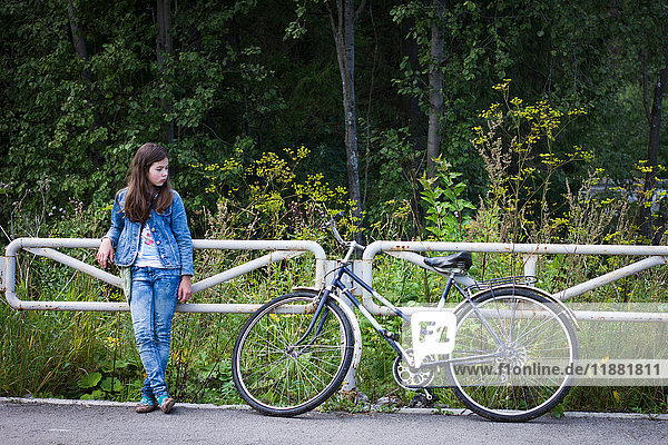 Teenager-Mädchen schaut auf ihr Fahrrad auf der Landstraße