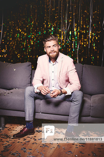 Man sitting on sofa at party  glitter covering floor