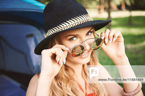 Portrait of young boho woman holding sunglasses at festival