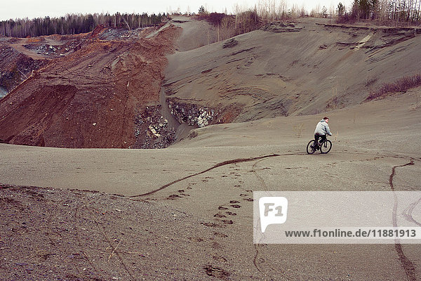 Rückansicht eines männlichen Mountainbikers beim Mountainbiken den Steinbruchhügel hinunter