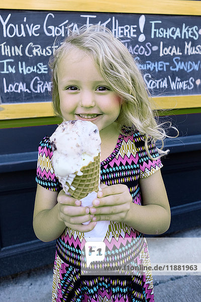 Porträt eines süßen blonden Mädchens  das eine große Eistüte hält