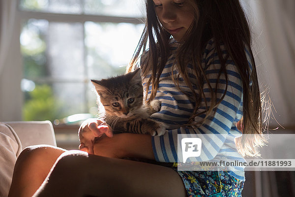 Mädchen mit Kätzchen auf Schoß sitzend