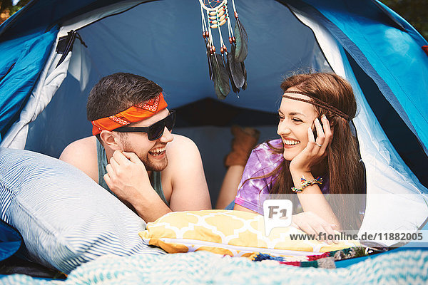 Young boho couple lying in tent at festival