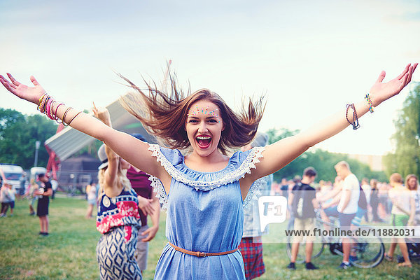 Young boho woman dancing and jumping for joy at festival