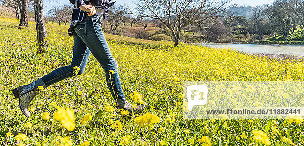 Reife Frau rennt durch ein Feld mit Wildblumen  niedriger Schnitt  Paso Robles  Kalifornien  USA