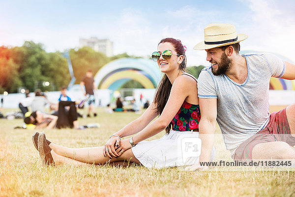 Couple sitting on grass together at festival