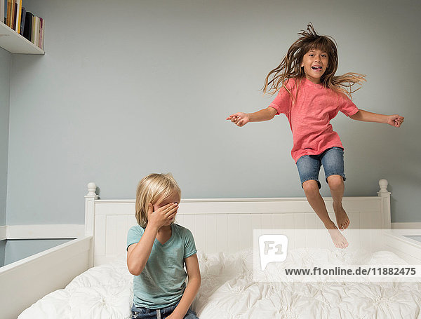 Girl in mid air jumping on bed