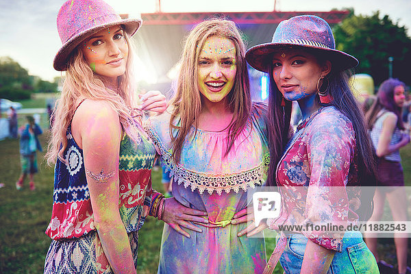 Portrait of three young boho women covered in coloured chalk powder at festival