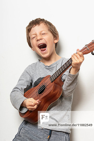 Boy playing ukulele  pulling face