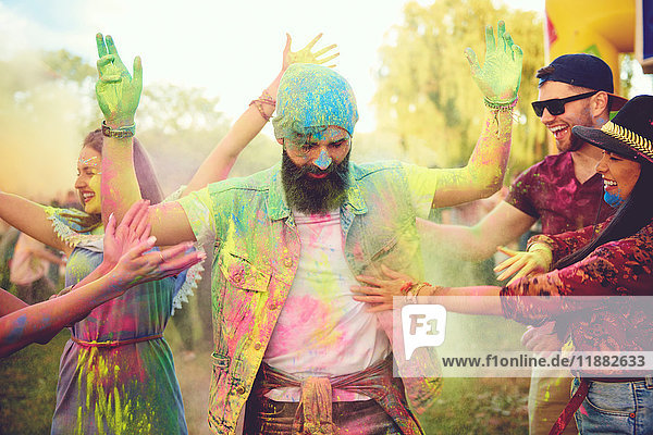 Junge erwachsene Freunde werfen mit farbigem Kreidepulver und tanzen auf dem Festival
