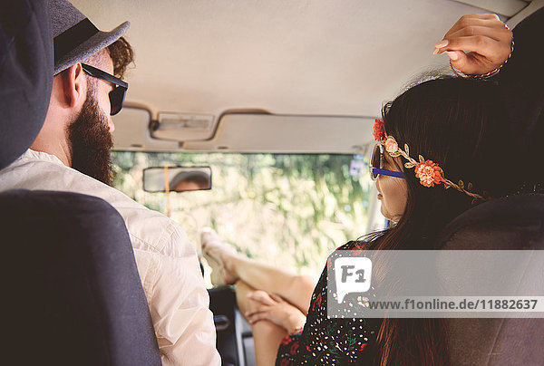 Over shoulder view of young boho couple with feet up in recreational van
