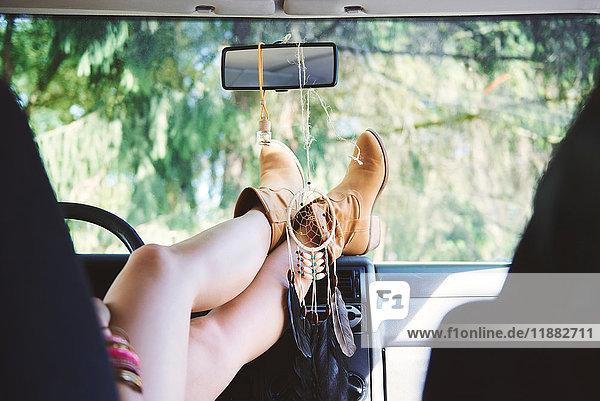 Young woman in ankle boots with feet up in recreational van