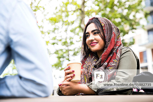 Woman wearing hijab enjoying coffee with friend