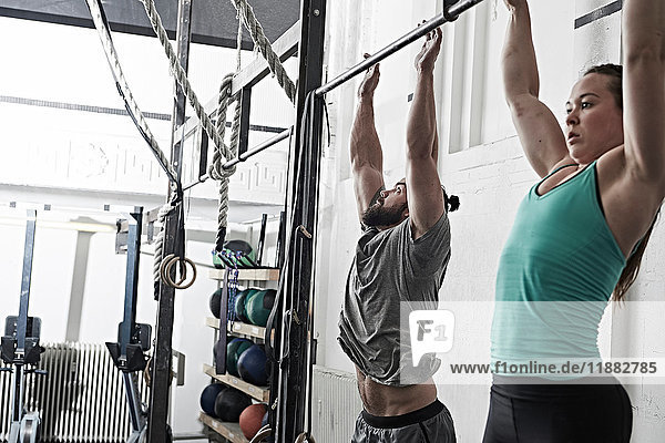 Couple doing chin-up in cross training gym
