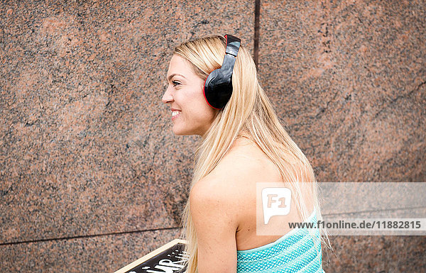 Mittlere erwachsene Frau  im Freien  Kopfhörer tragend  nach unten schauend