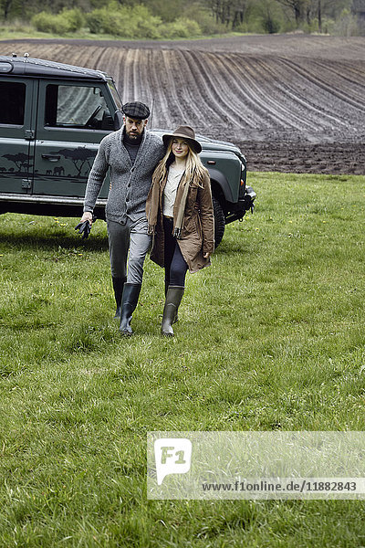 Country couple in outdoor clothes walking up field