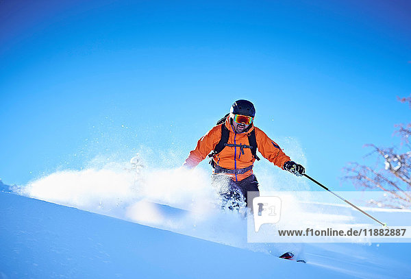 Mann fährt auf Skiern einen schneebedeckten Berghang hinunter  Aspen  Colorado  USA