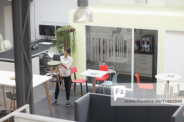 Young female sales manager inspecting office stool in office furniture store