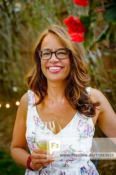 Porträt einer Frau auf Gartenparty  ein Glas Wein haltend  lächelnd