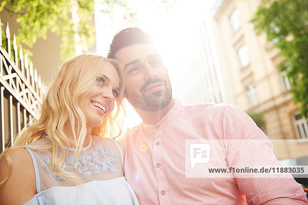 Portrait of couple in sunlight looking away smiling