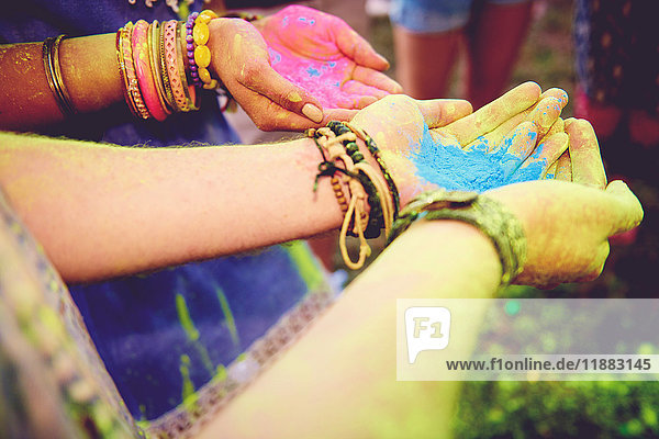 Pink and blue chalk cupped in young couples hands at festival
