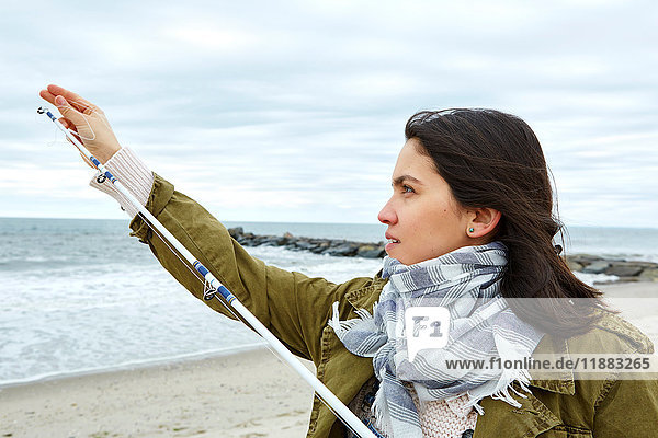 Junge Frau beim Anpassen der Angelschnur am Strand