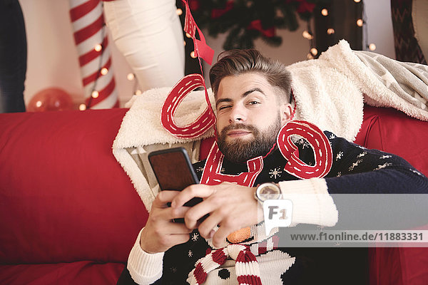 Portrait of young man wrapped in christmas decorations at christmas party