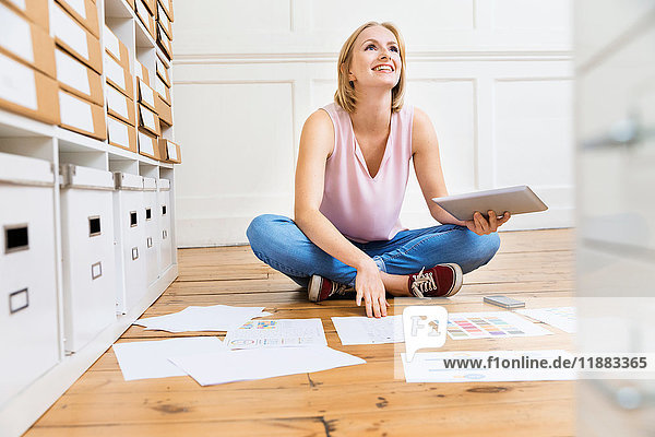 Female designer sitting on floor creating mood board in creative studio