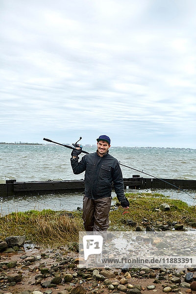 Porträt eines jungen männlichen Seefischers mit Angelrute über der Schulter