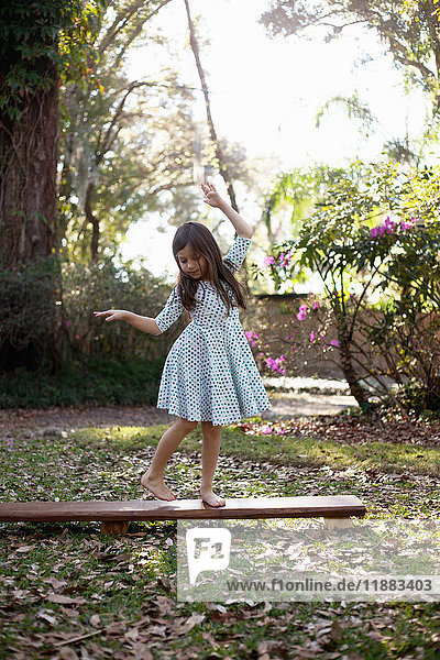 Girl balancing on wooden step in shaded garden