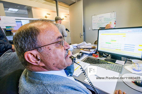 Über-Schulter-Ansicht eines Managers beim Telefonieren am Büroschreibtisch