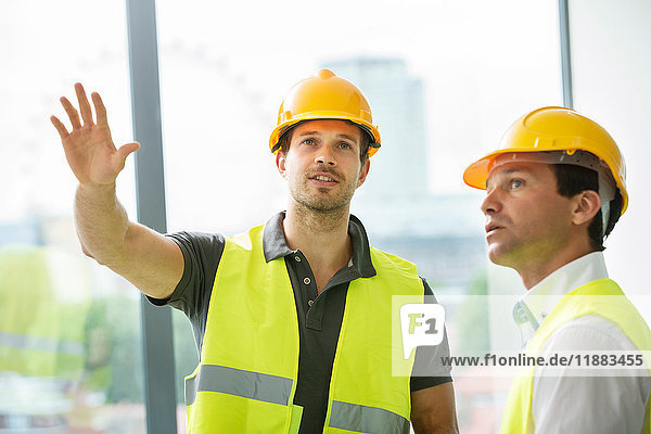Two men wearing hi vis vest  having discussion in newly constructed office space