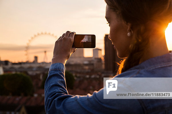 Junge Frau fotografiert Skyline bei Sonnenuntergangs-Dachparty in London  Großbritannien