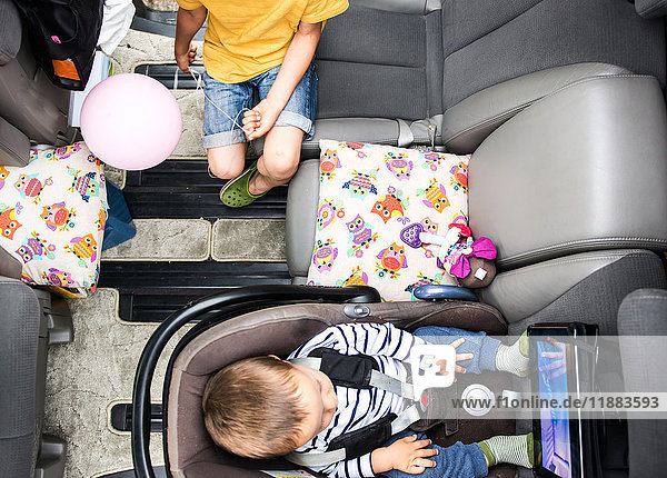 Baby und großer Bruder sehen sich im Auto einen Film an