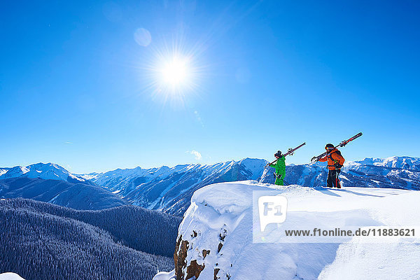 Zwei männliche Skifahrer schauen von einem schneebedeckten Bergrücken aus  Aspen  Colorado  USA