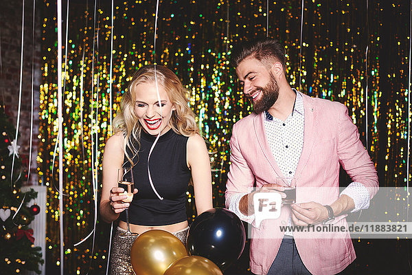 Man and woman at party  holding drinks  laughing