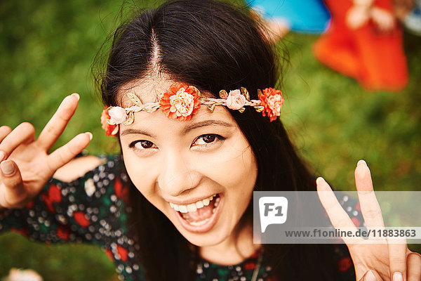 Porträt einer jungen Boho-Frau  die beim Festival ein Friedenszeichen setzt