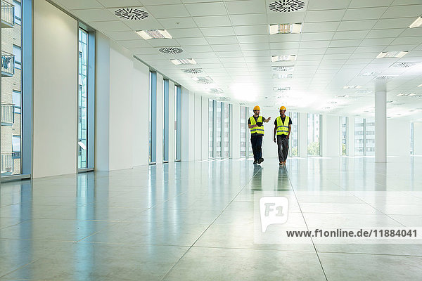 Two construction workers walking through empty office space