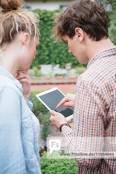 Ehepaar im Garten mit digitalem Tablett