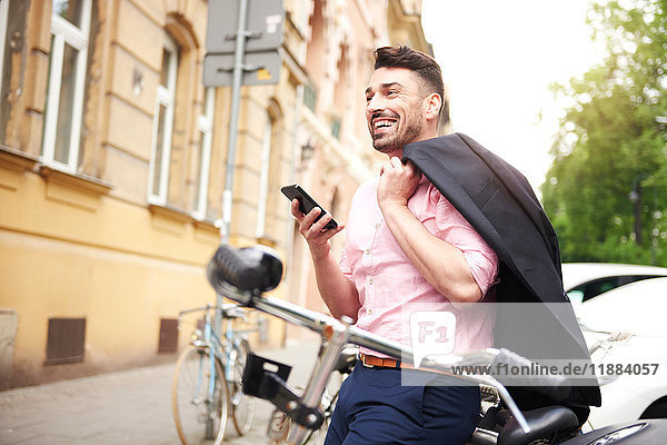 Man with bicycle holding smartphone smiling