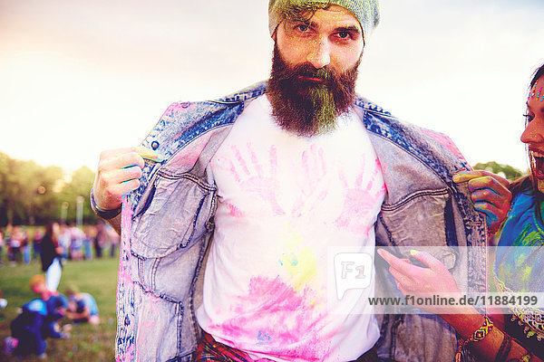 Porträt eines jungen männlichen Hipsters mit Kreidehandabdrücken auf T-Shirt beim Festival