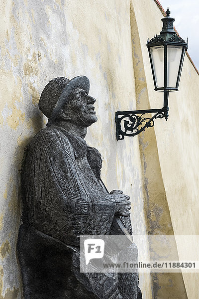 Statue eines Mannes  der neben einer Lampe an der Wand lehnt; Prag  Tschechische Republik'.