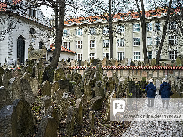 Zwei ältere Frauen gehen einen Weg neben einem alten jüdischen Friedhof entlang; Prag  Tschechische Republik'.